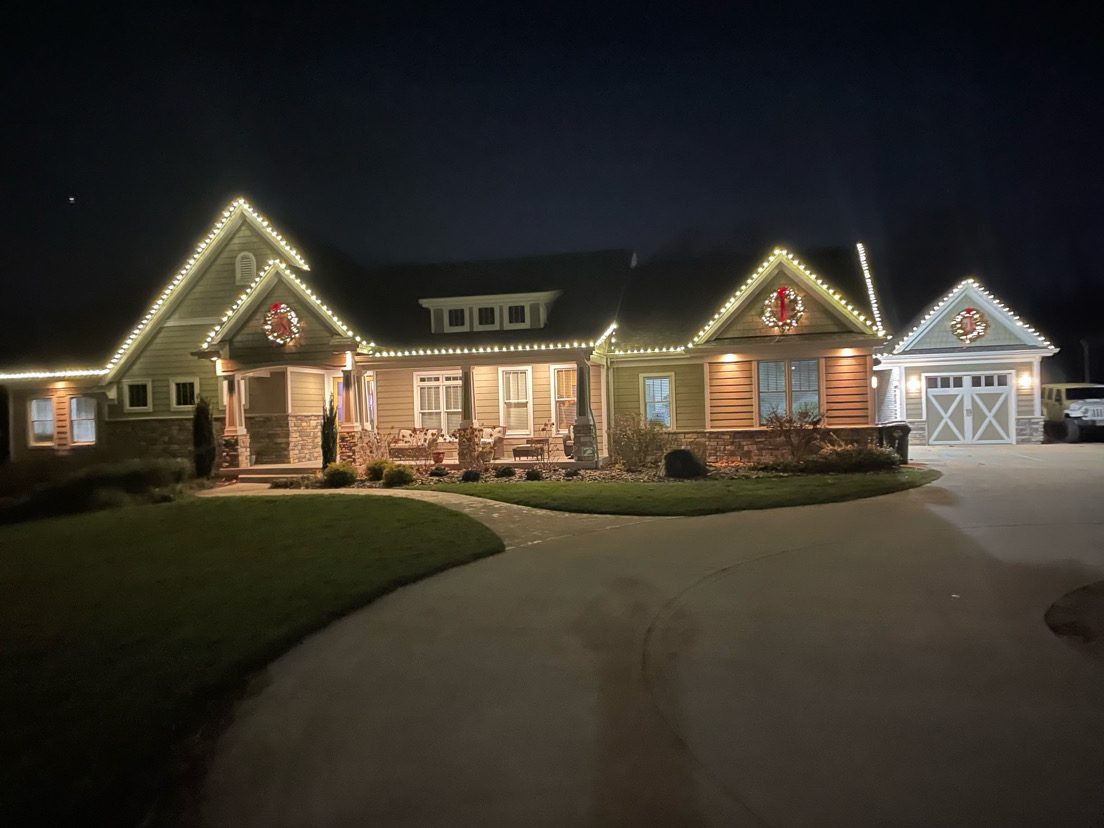 Home decorated with warm white Christmas lights and wreaths at night